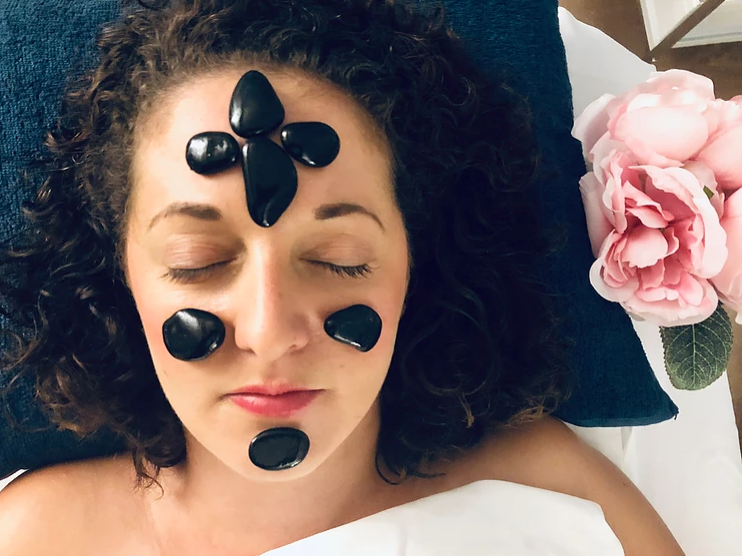 Woman with stones on her face receiving a facial treatment