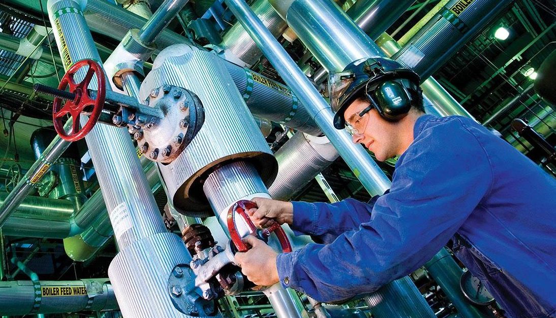 Man wearing safety gear, fixing a pipe